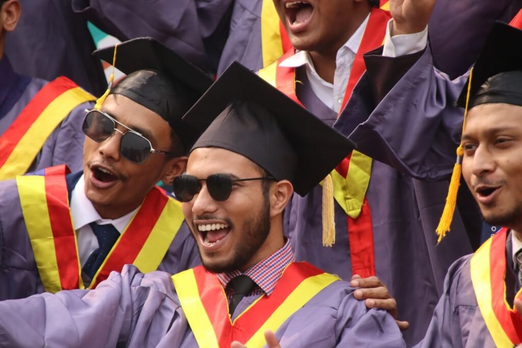 Group of diverse graduates celebrating with enthusiasm in convocation attire.